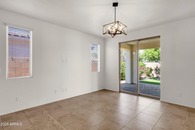 empty room featuring a wealth of natural light, a chandelier, and baseboards