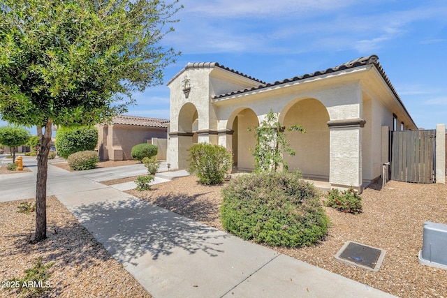 view of front of home with a tile roof, a gate, and stucco siding