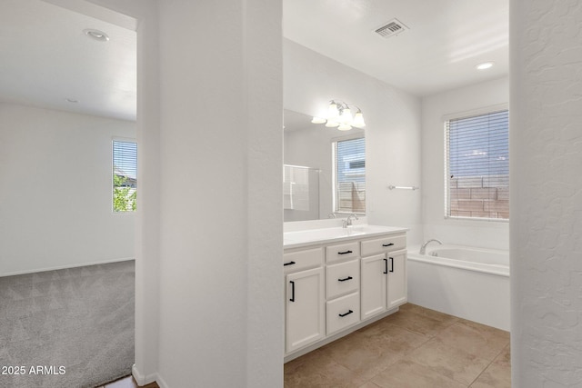 bathroom with a bath, vanity, and visible vents