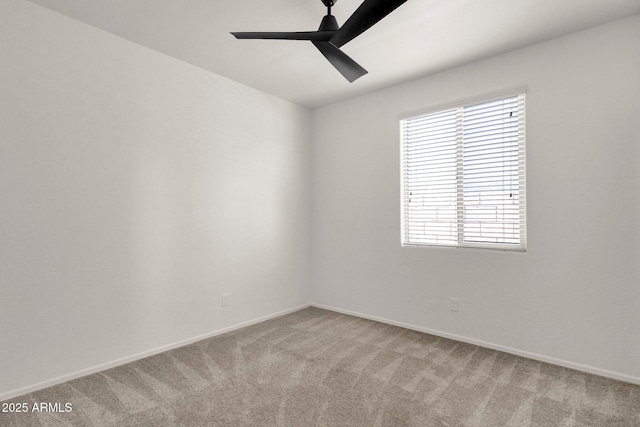 spare room featuring light carpet, baseboards, and a ceiling fan