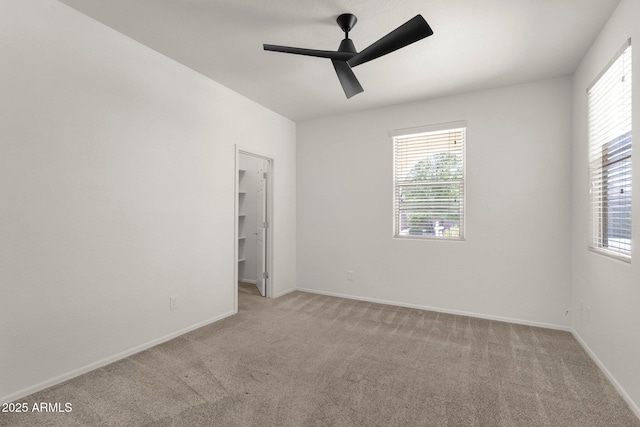 unfurnished bedroom featuring light carpet, baseboards, and a ceiling fan
