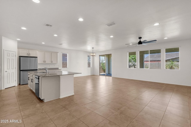 kitchen with freestanding refrigerator, white cabinets, visible vents, recessed lighting, and open floor plan
