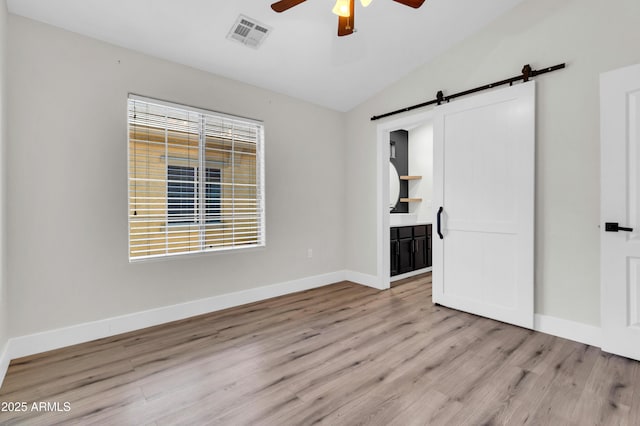 1350 S Greenfield Rd Unit 1166, Mesa, AZ 85206 - unfurnished bedroom with a barn door, vaulted ceiling, wood finished floors, baseboards, and connected bathroom