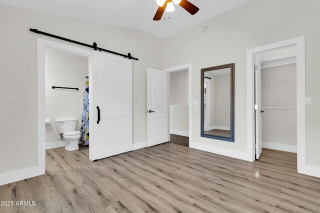 1350 S Greenfield Rd Unit 1166, Mesa, AZ 85206 - unfurnished bedroom featuring a barn door, wood finished floors, vaulted ceiling, baseboards, and a walk in closet
