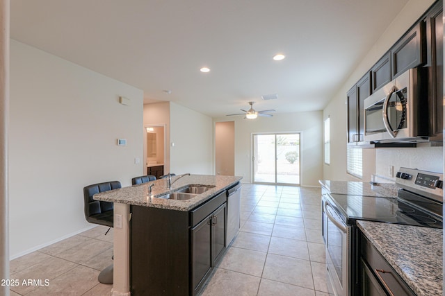 kitchen featuring sink, light tile patterned floors, a kitchen breakfast bar, stainless steel appliances, and a kitchen island with sink