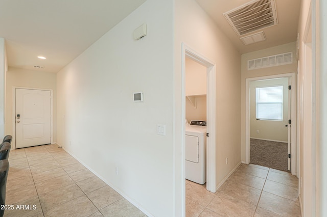 hallway featuring light tile patterned flooring and washer / dryer