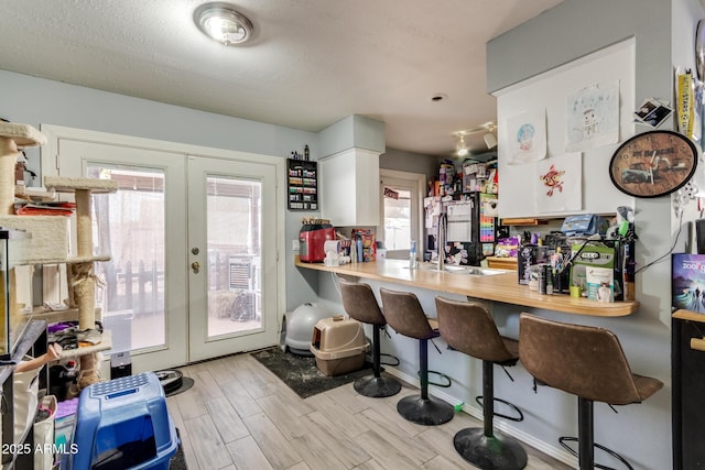 kitchen with white cabinetry, french doors, a kitchen breakfast bar, sink, and kitchen peninsula