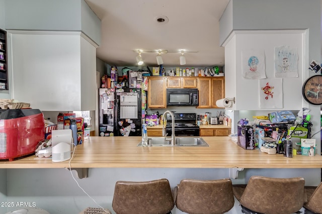 kitchen with sink, black appliances, and kitchen peninsula