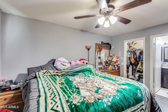 bedroom featuring ceiling fan, hardwood / wood-style flooring, ensuite bathroom, and a closet