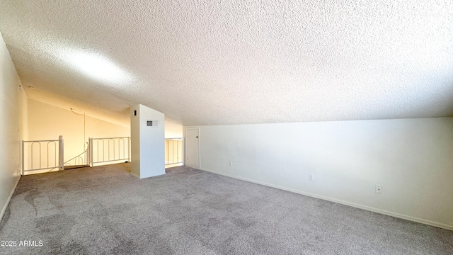 additional living space featuring lofted ceiling, carpet floors, and a textured ceiling