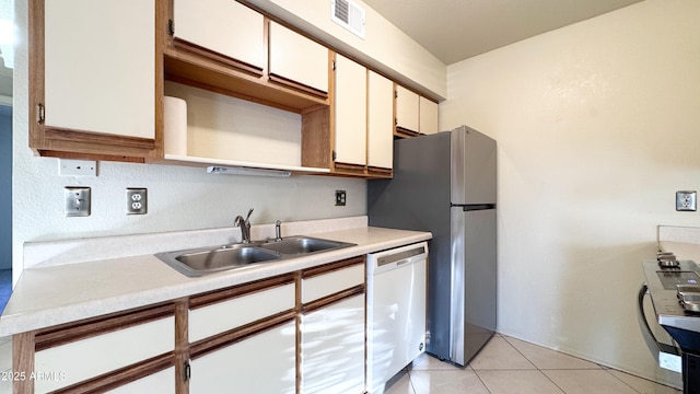 kitchen featuring light tile patterned floors, dishwasher, sink, and white cabinets