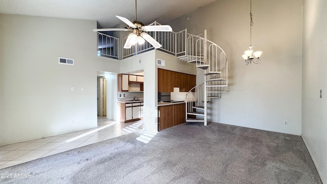 unfurnished living room featuring ceiling fan with notable chandelier, sink, light carpet, and a towering ceiling