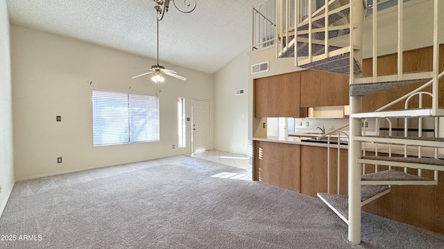 kitchen featuring ceiling fan, high vaulted ceiling, light carpet, and a textured ceiling