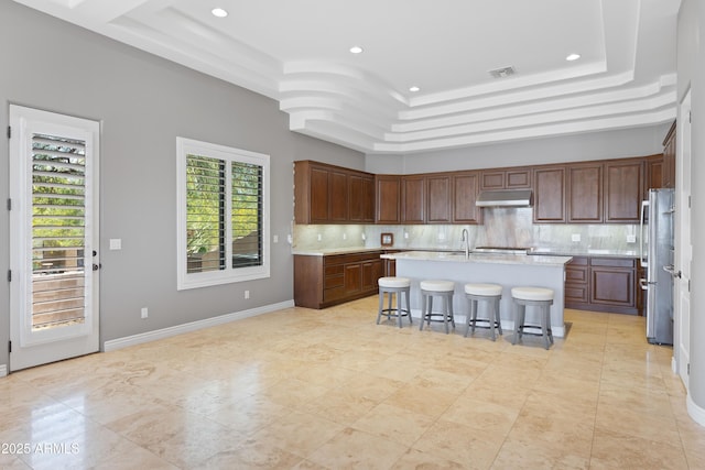 16246 E Gamble Ln, Scottsdale, AZ 85262 - kitchen featuring a raised ceiling, freestanding refrigerator, light countertops, under cabinet range hood, and backsplash