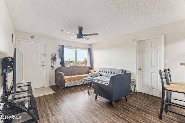 living area with a textured ceiling, a ceiling fan, and dark wood-style flooring