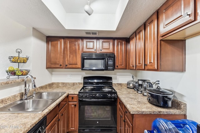 kitchen with a tray ceiling, light countertops, visible vents, a sink, and black appliances