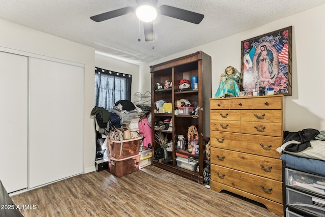 bedroom featuring a ceiling fan, a closet, a textured ceiling, and wood finished floors