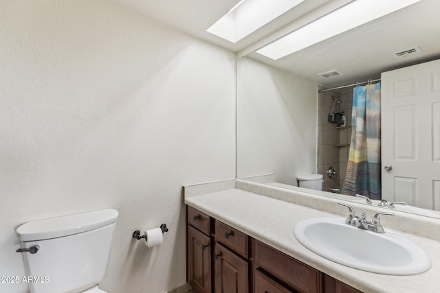 bathroom with toilet, a skylight, visible vents, and vanity