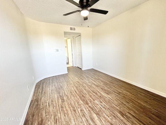 unfurnished room with baseboards, wood finished floors, visible vents, and a ceiling fan