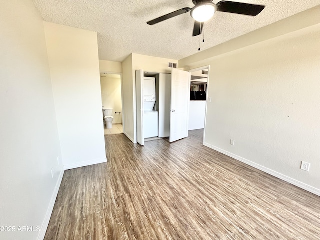 unfurnished bedroom featuring wood finished floors, a textured ceiling, connected bathroom, baseboards, and visible vents
