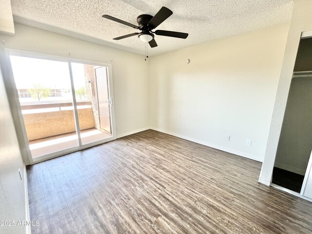 empty room with wood finished floors, a textured ceiling, a ceiling fan, and baseboards