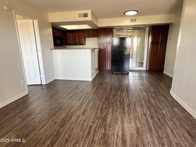 unfurnished living room with baseboards, visible vents, a textured ceiling, and dark wood-style floors