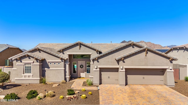 ranch-style home featuring stucco siding, an attached garage, and decorative driveway