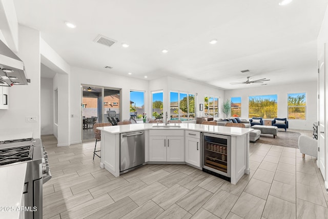 kitchen featuring visible vents, a sink, ceiling fan, stainless steel appliances, and wine cooler