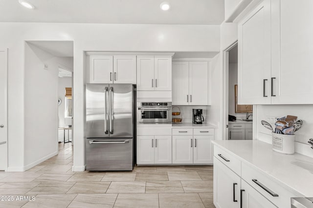 kitchen featuring baseboards, recessed lighting, stainless steel appliances, light countertops, and white cabinets