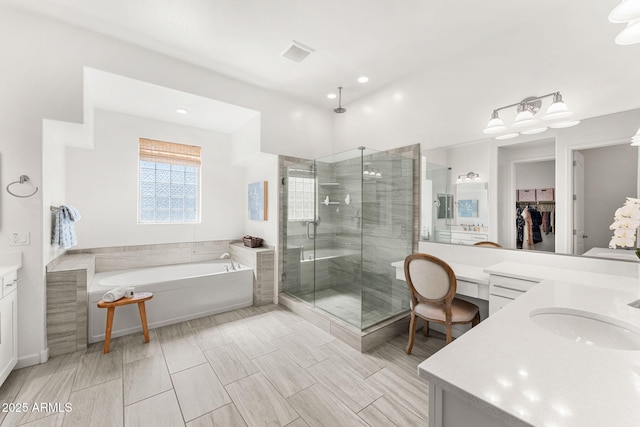 full bathroom featuring a spacious closet, visible vents, a garden tub, a stall shower, and vanity