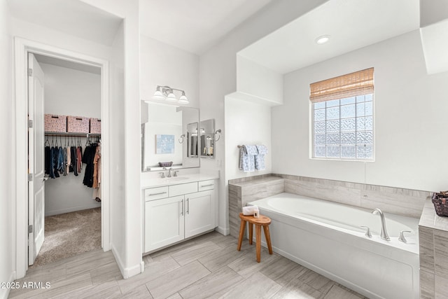 bathroom with vanity, a spacious closet, and a bath