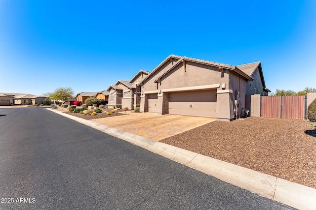 single story home featuring fence, stucco siding, decorative driveway, a garage, and a gate