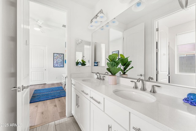 full bathroom with double vanity, visible vents, wood finished floors, and a sink