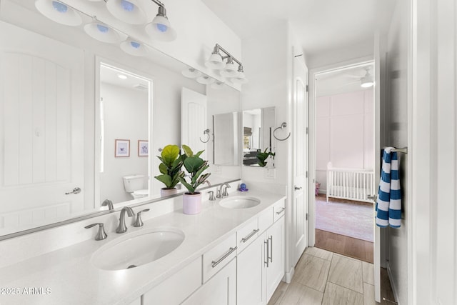 full bath featuring double vanity, toilet, wood finished floors, and a sink