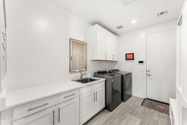 washroom with cabinet space, washing machine and dryer, visible vents, and a sink