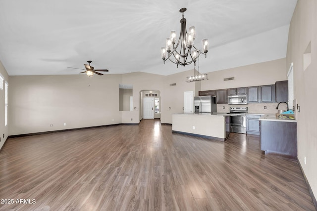 unfurnished living room with ceiling fan with notable chandelier, wood finished floors, arched walkways, and baseboards