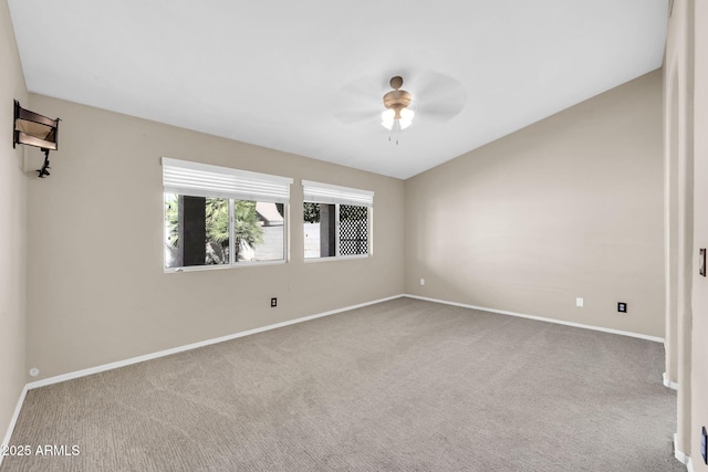 carpeted spare room with lofted ceiling, ceiling fan, and baseboards