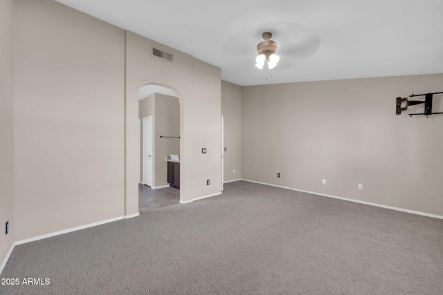 unfurnished room with arched walkways, ceiling fan, carpet flooring, visible vents, and baseboards