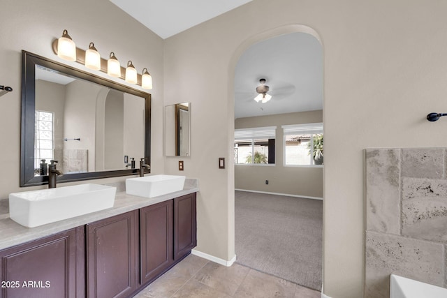 full bathroom with double vanity, tile patterned flooring, baseboards, and a sink