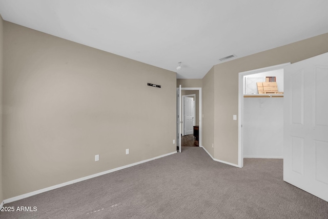 unfurnished bedroom featuring carpet flooring, visible vents, baseboards, a spacious closet, and a closet