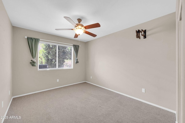 carpeted spare room with a ceiling fan and baseboards