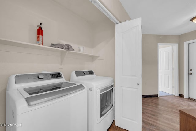 laundry area featuring laundry area, baseboards, washing machine and clothes dryer, and wood finished floors