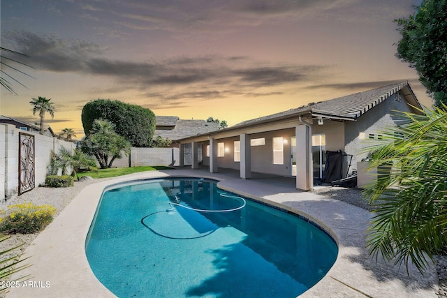 pool at dusk with a fenced in pool, a fenced backyard, and a patio