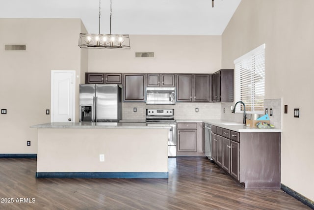 kitchen featuring appliances with stainless steel finishes, visible vents, a sink, and a towering ceiling