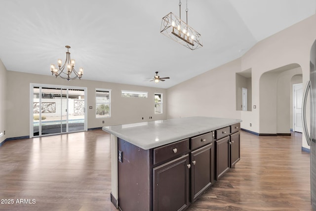 kitchen with arched walkways, lofted ceiling, open floor plan, wood finished floors, and dark brown cabinets