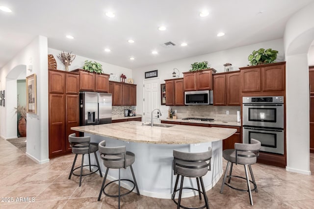 800 W Sycamore Ct, Litchfield Park, AZ 85340 - kitchen featuring a sink, stainless steel appliances, a large island, backsplash, and arched walkways
