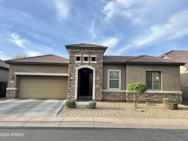 prairie-style house with driveway, stucco siding, a garage, and stone siding
