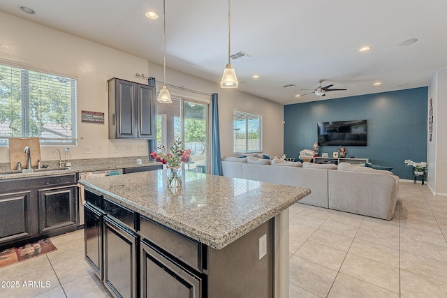 kitchen with a sink, light tile patterned flooring, visible vents, a ceiling fan, and light stone countertops