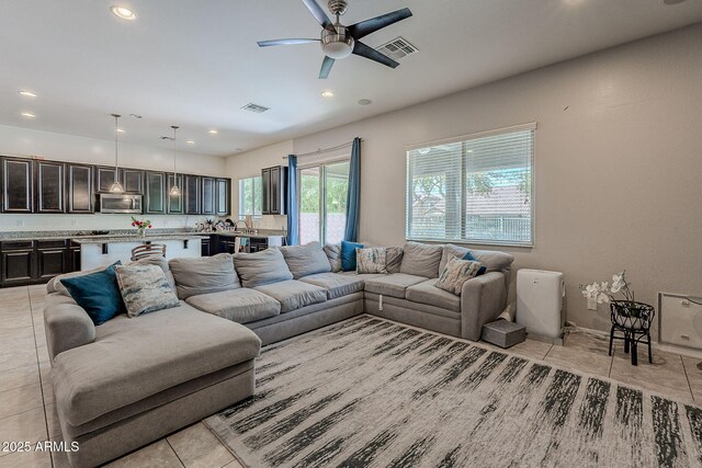 living room with light tile patterned flooring, visible vents, and a ceiling fan