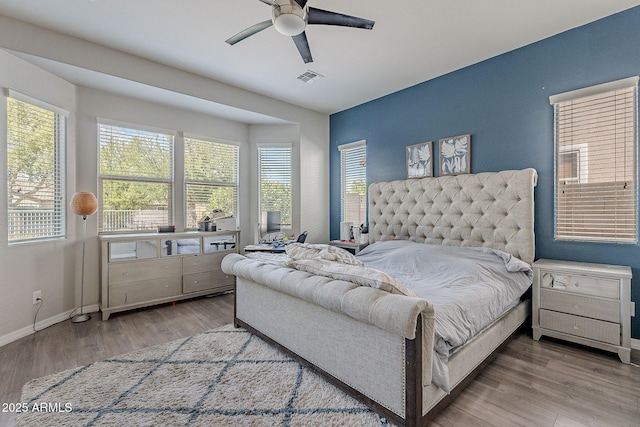 bedroom with baseboards, ceiling fan, visible vents, and wood finished floors